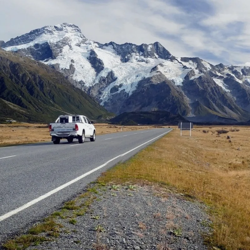 White pickup on a road with the snowy Andes behind